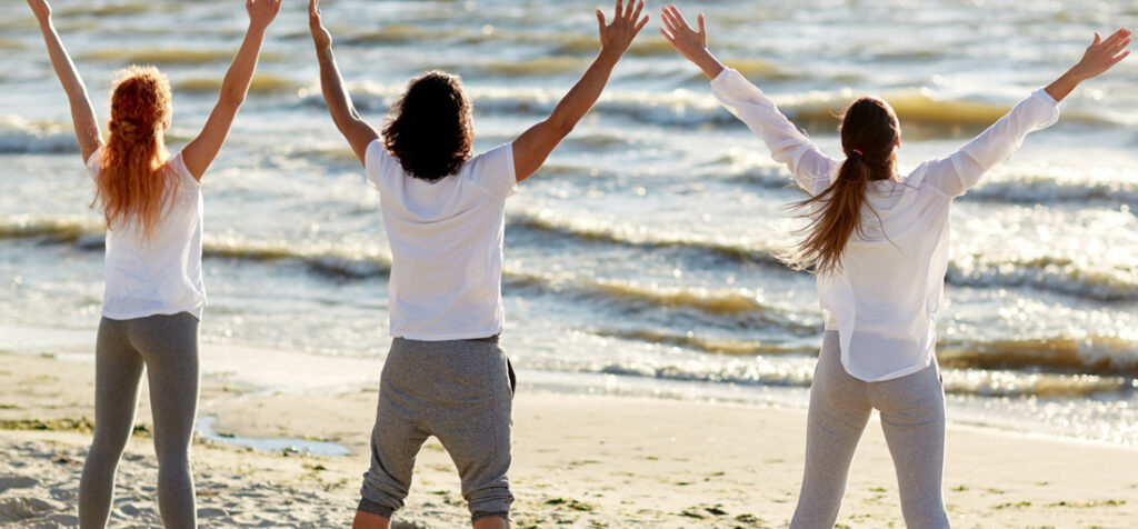 Three people at the beach doing 5-pointed star pose in yoga in article Tackling clinical depression using group exercise activities that benefit YOU and build accountability