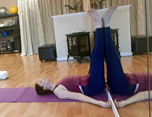 Instructor in savasana (resting pose) legs up the wall after class