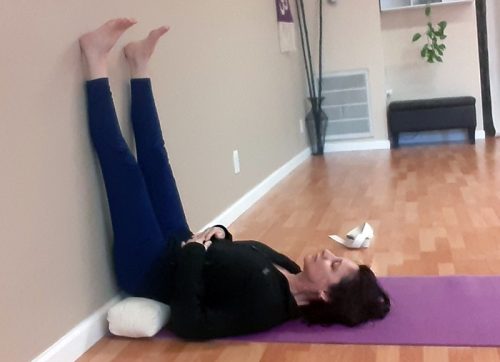 Savasana with elevated hips under cushion. Instructor, Gwenn Jones
